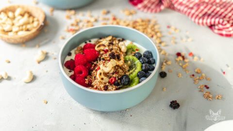 Frühstücksbowl mit frischen Früchten, Müsli und gerösteten Cashewkernen.