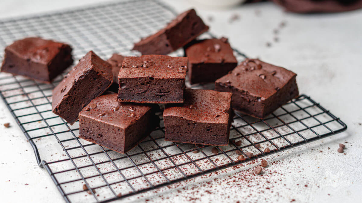 Low Carb Brownies ohne Zucker auf einem schwarzen Kuchengitter mit etwas Kakao bestreut.