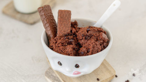 Keksteig ohne Zucker in einer weißen Schüssel. Im Cookie Dough stecken zwei dünne Schokoladen-Waffeln.