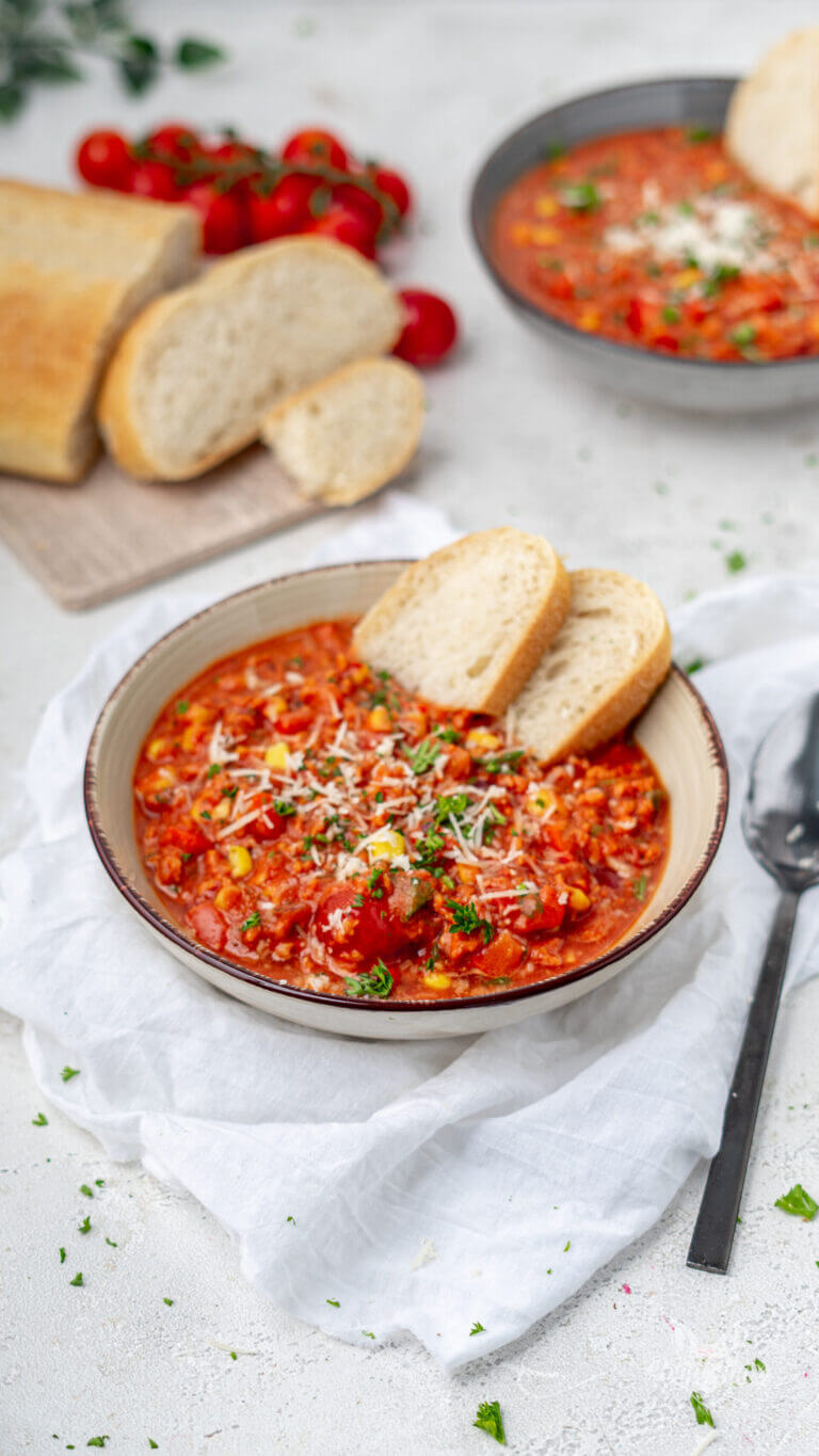 kohlenhydratarme Pizzasuppe mit viel Gemüse und ohne Pilze. Getoppt mit frischem Parmesan. Serviert in einem tiefen Teller. Zwei Scheiben Brot wurden dazu gereicht.