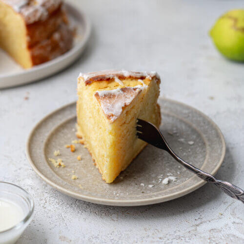 schneller, fluffiger Zitronenkuchen ohne Zucker auf einem Kuchenteller. Eine Gabel steckt in der Seite.