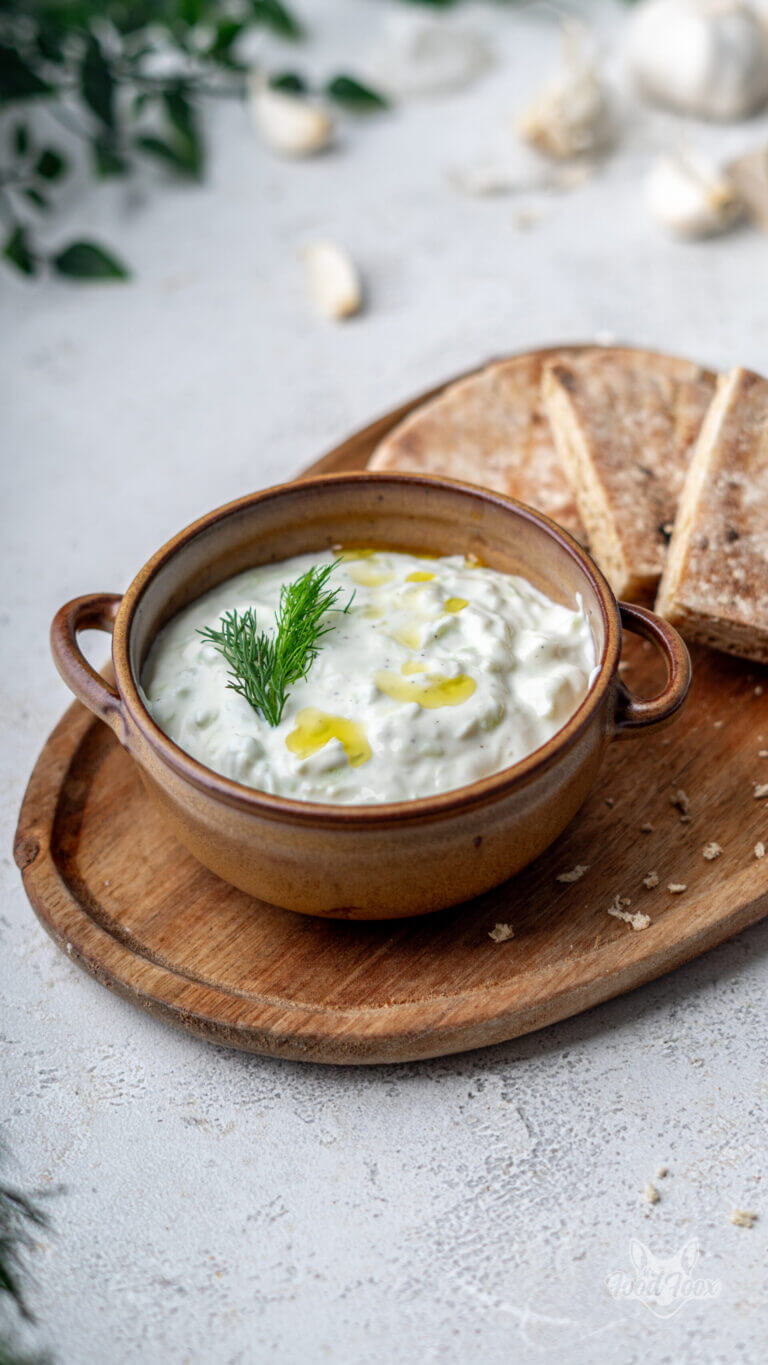 kalorienarmes griechisches Tsatsiki in einer braunen Servierschale garniert mit Dill und Olivenöl.