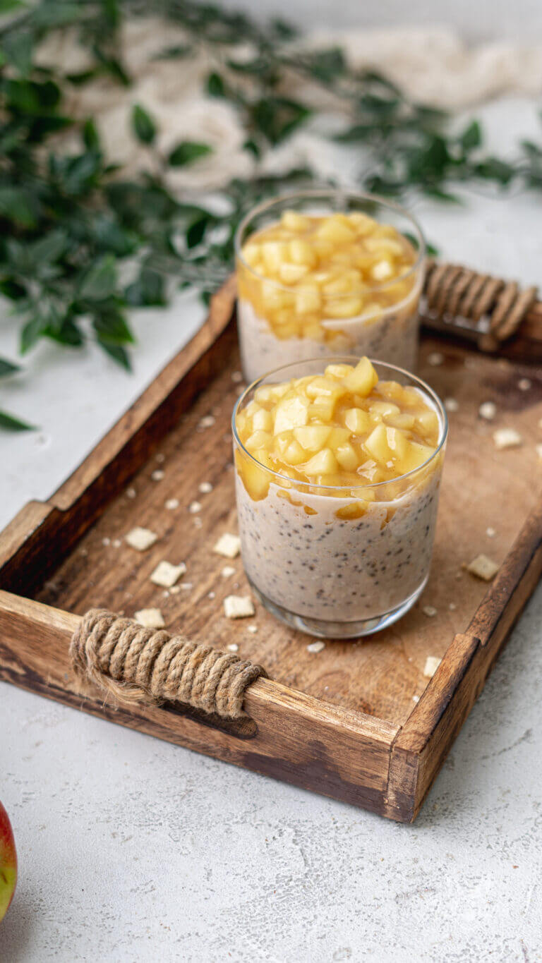 Overnight Oats mit Chiasamen. Serviert in zwei Gläsern, getippt mit Apfelkompott. Zuckerfrei und proteinreich.