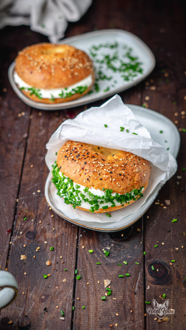 proteinreiche Bagels mit Frischkäse und Schnittlauch, selbst gemacht. angerichtet auf einem grauen Teller