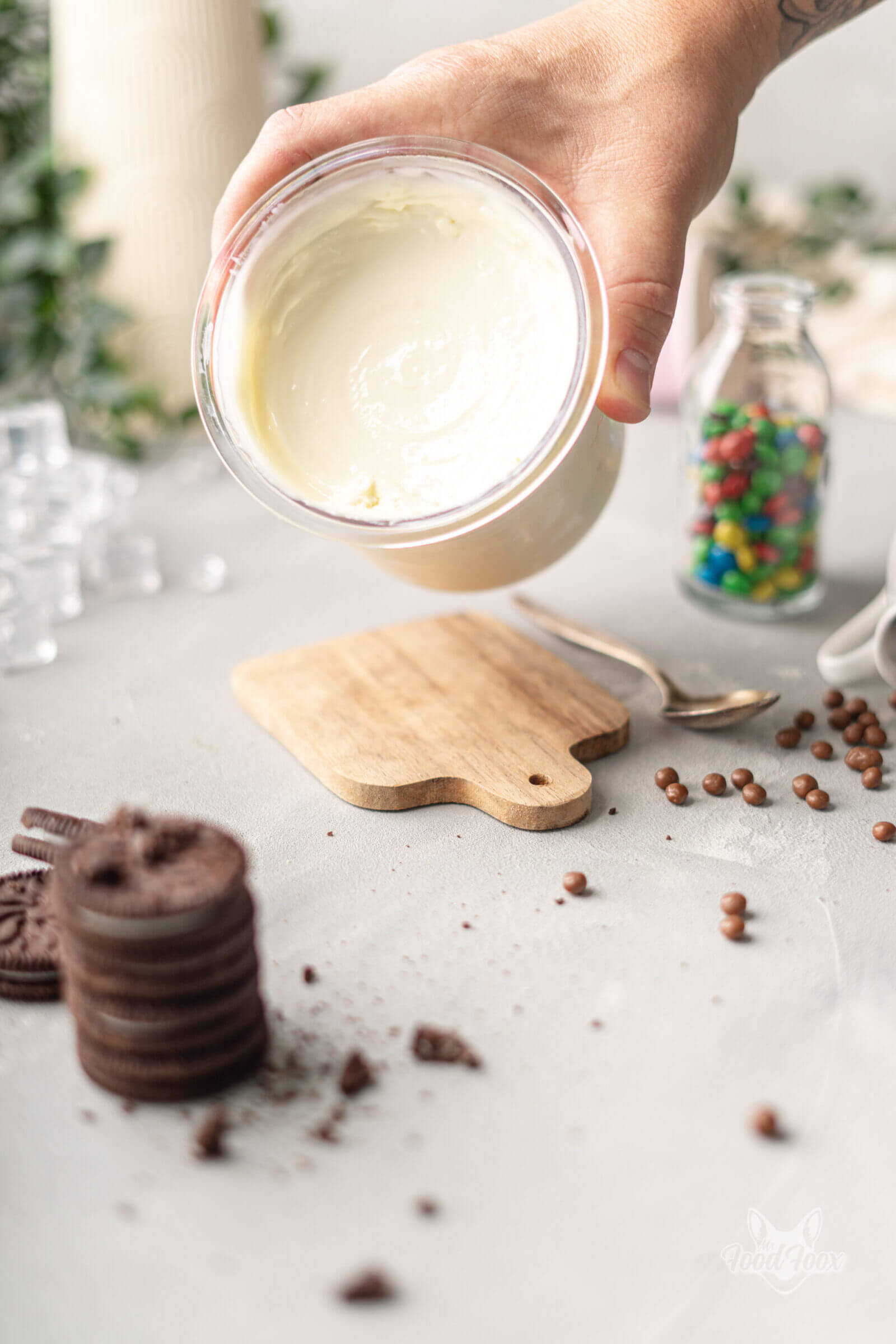 Ein Becher voller cremigem Protein Eis aus der Ninja Creami Eismaschine. Im Vordergrund sind verschiedene Eis-Toppings wie Kekse, bunte Schokolinsen und Schokokugeln zu sehen