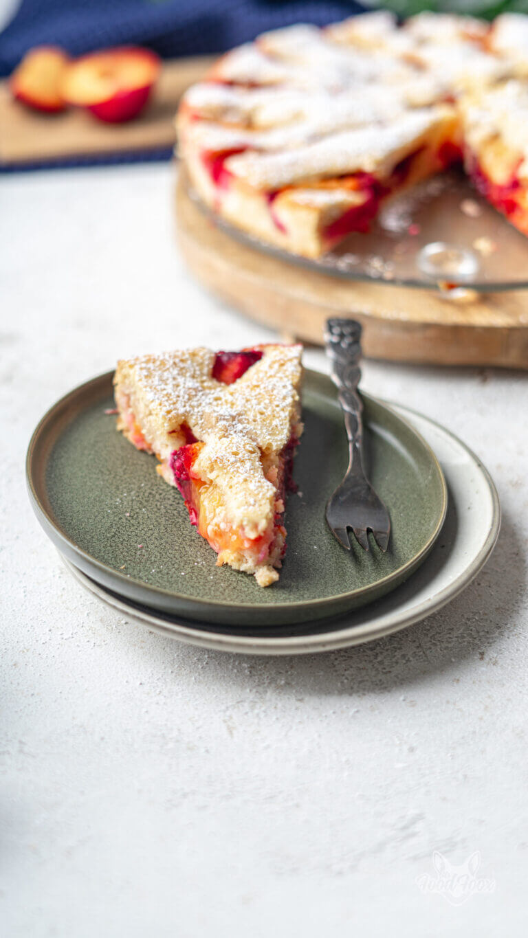 Ein Stück saftiger Pflaumenkuchen auf einem Kuchenteller, die Kuchengabel liegt daneben.