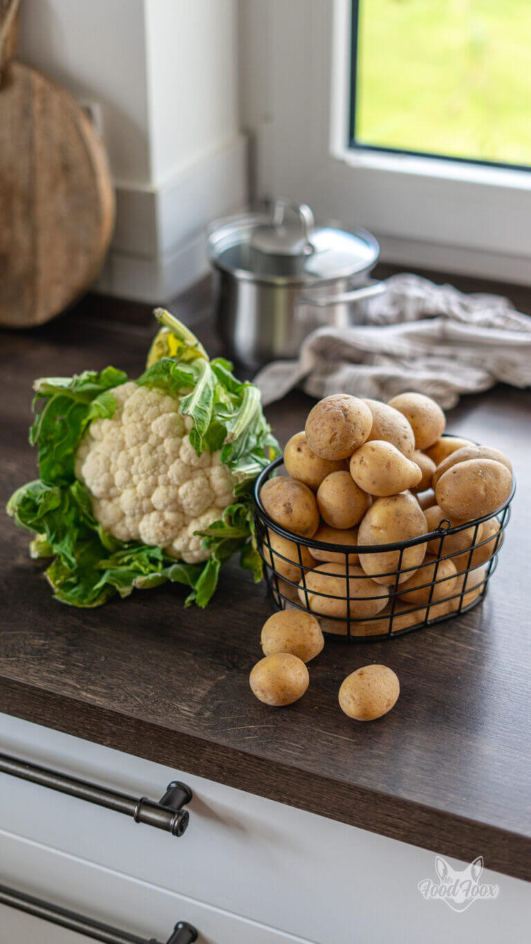 frischer Blumenkohl neben einigen Kartoffeln, bereit um zu kalorienarmen Kartoffelbrei mit Blumenkohl zu werden.